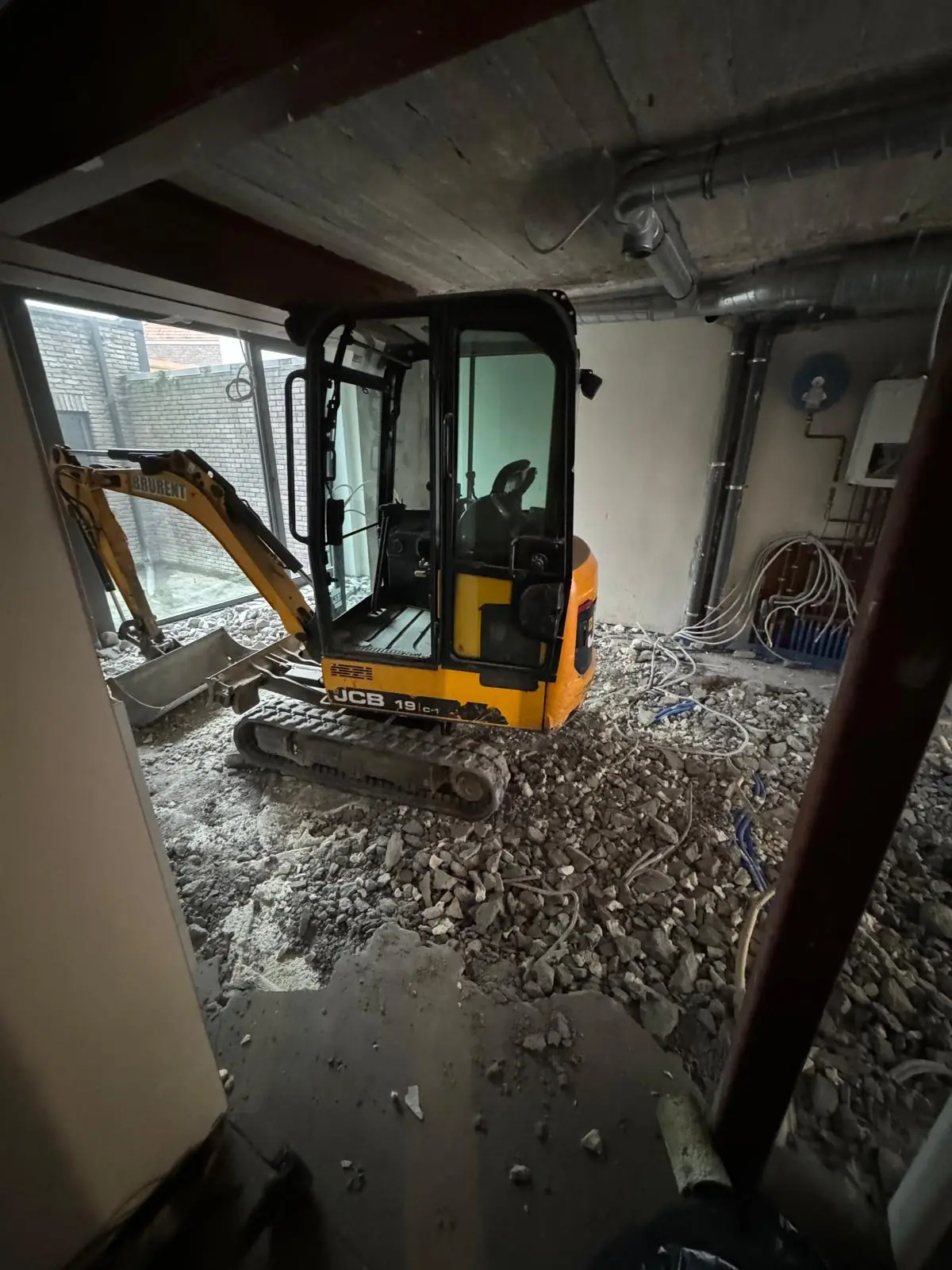 Mini-pelle à l'intérieur du bâtiment pendant la démolition